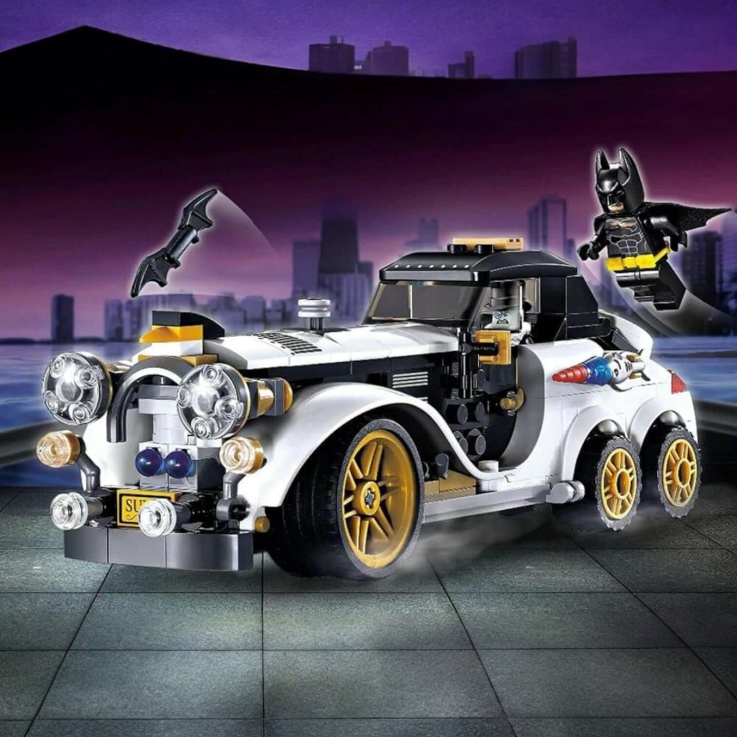 Lego-style building block set featuring a white classic car with gold wheels, Batman minifigure flying above, and Batarang accessory. Perfect for kids to assemble superhero adventures. www.usmile.toys
